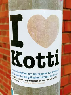 Sticker expressing love for the Kottbusser Tor neighborhood in Berlin and advocating against rising rents.  It features a heart design and contact information for a tenant community.