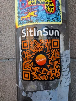 Street sticker A vertically oriented die-cut sticker set against a black background with a white border. At the top, the bold white text reads 'SitInSun' accompanied by a Swedish tagline in smaller font: 'Hitta en uteservering med sol nära dig!'. Beneath the text is a prominent orange dot-matrix style QR code featuring an orange circular sun emblem in the center with the brand name 'SitInSun' written in white inside.