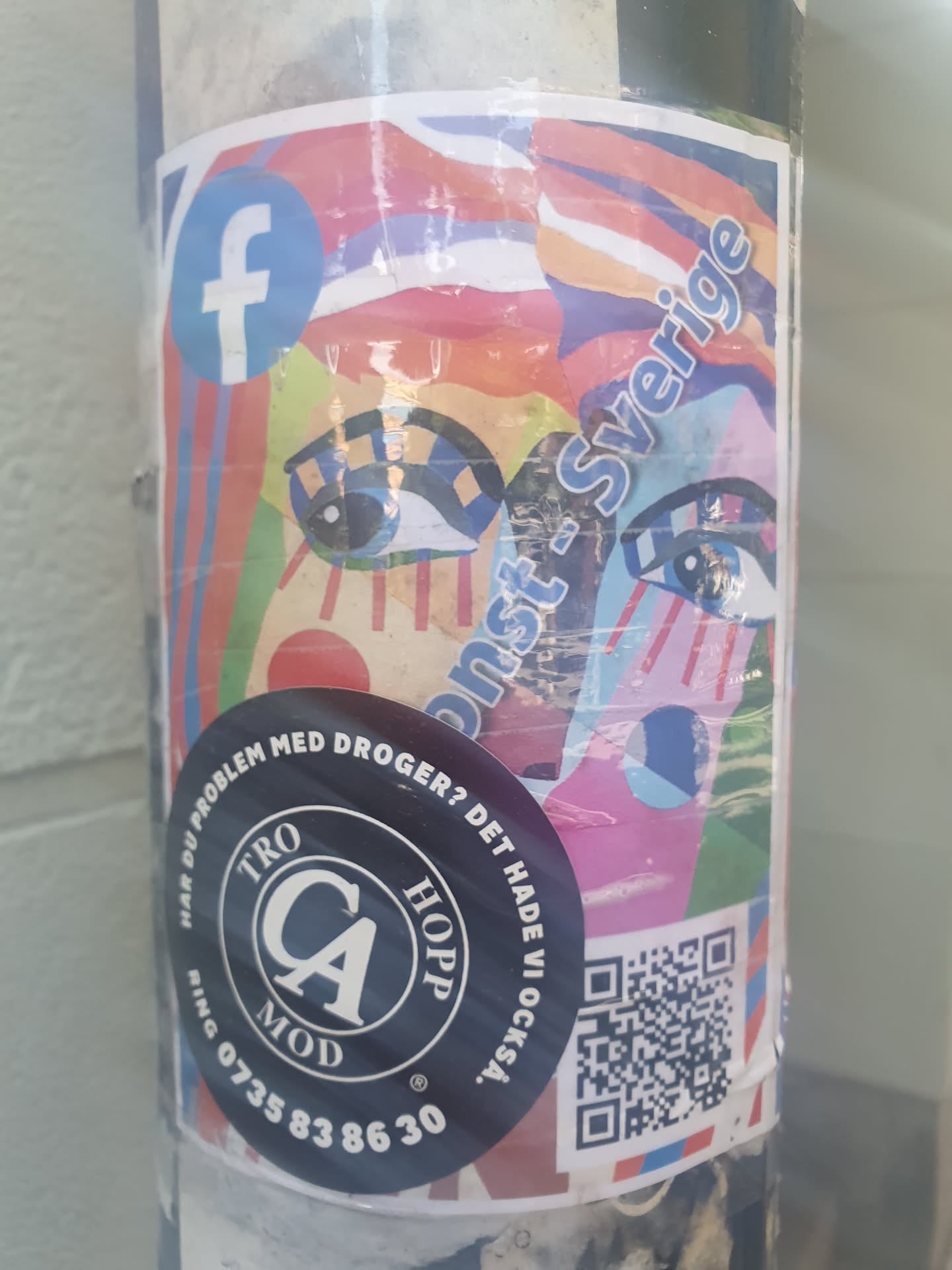 A colorful sticker featuring an abstract artwork with eyes and the text "Konst-Sverige". It also includes a Facebook logo, a QR code, and a round sticker with text in Swedish, presumably about drug problems and hope, with a phone number. 