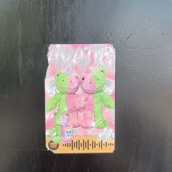 Pink and green frog plushies sticker with a Spotify code. The sticker features two frog plushies holding hands, with a smaller frog plushie holding a drink below them. The background is pink with sparkles and the word "AVATIC" written in a stylized font at the top. A Spotify code is visible at the bottom.