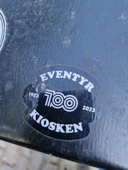 Black and white sticker commemorating the 100th anniversary of Eventyr Kiosken (1923-2023).