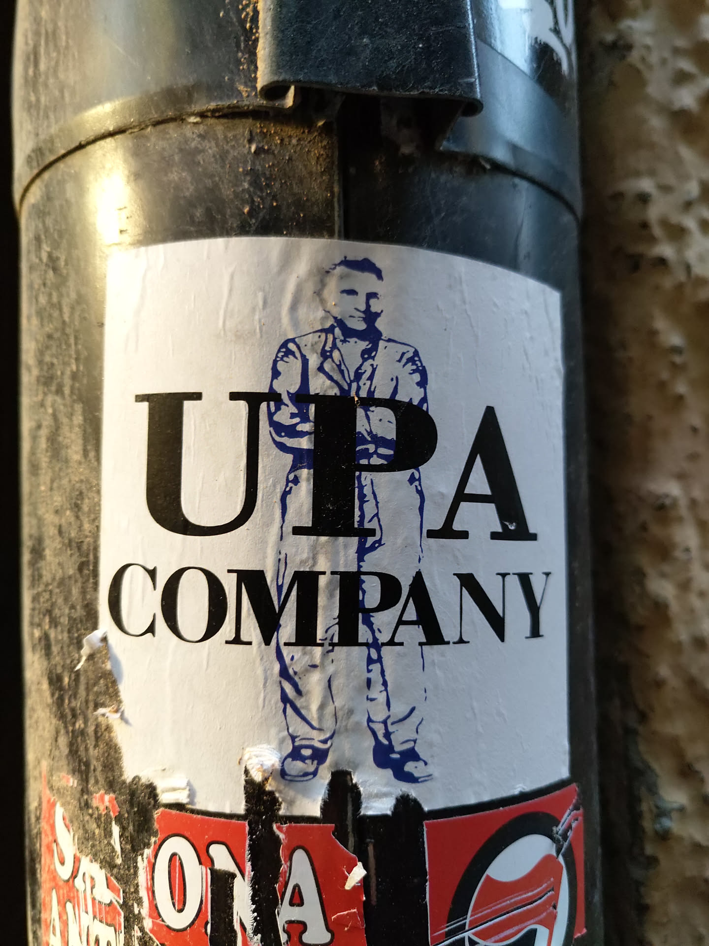 A sticker featuring a stylized illustration of a man with the text "UPA COMPANY" printed prominently. The man appears to be wearing a suit and has his arms crossed. The style is minimalist, with bold black lettering on a white background and the figure in blue.