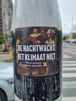A sticker featuring a detail of Rembrandt's 'The Night Watch' with text overlay in Dutch.  The text translates to: 'The Night Watch, not the climate. Rijksmuseum, break with ING!' It appears to be a protest or activism sticker.