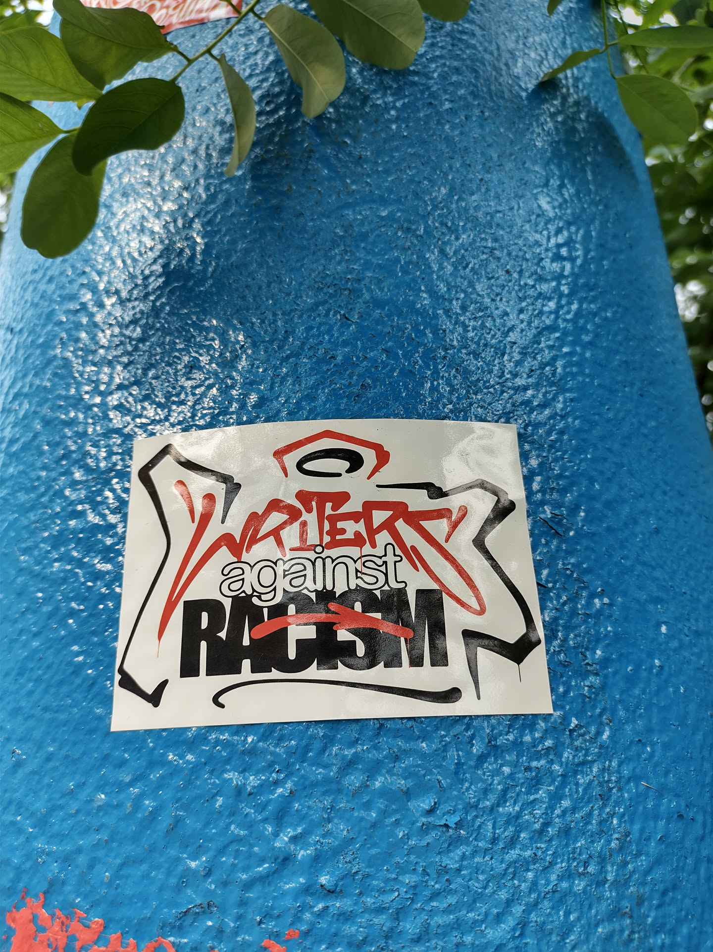 A sticker expressing solidarity against racism. It features stylized graffiti-like lettering.