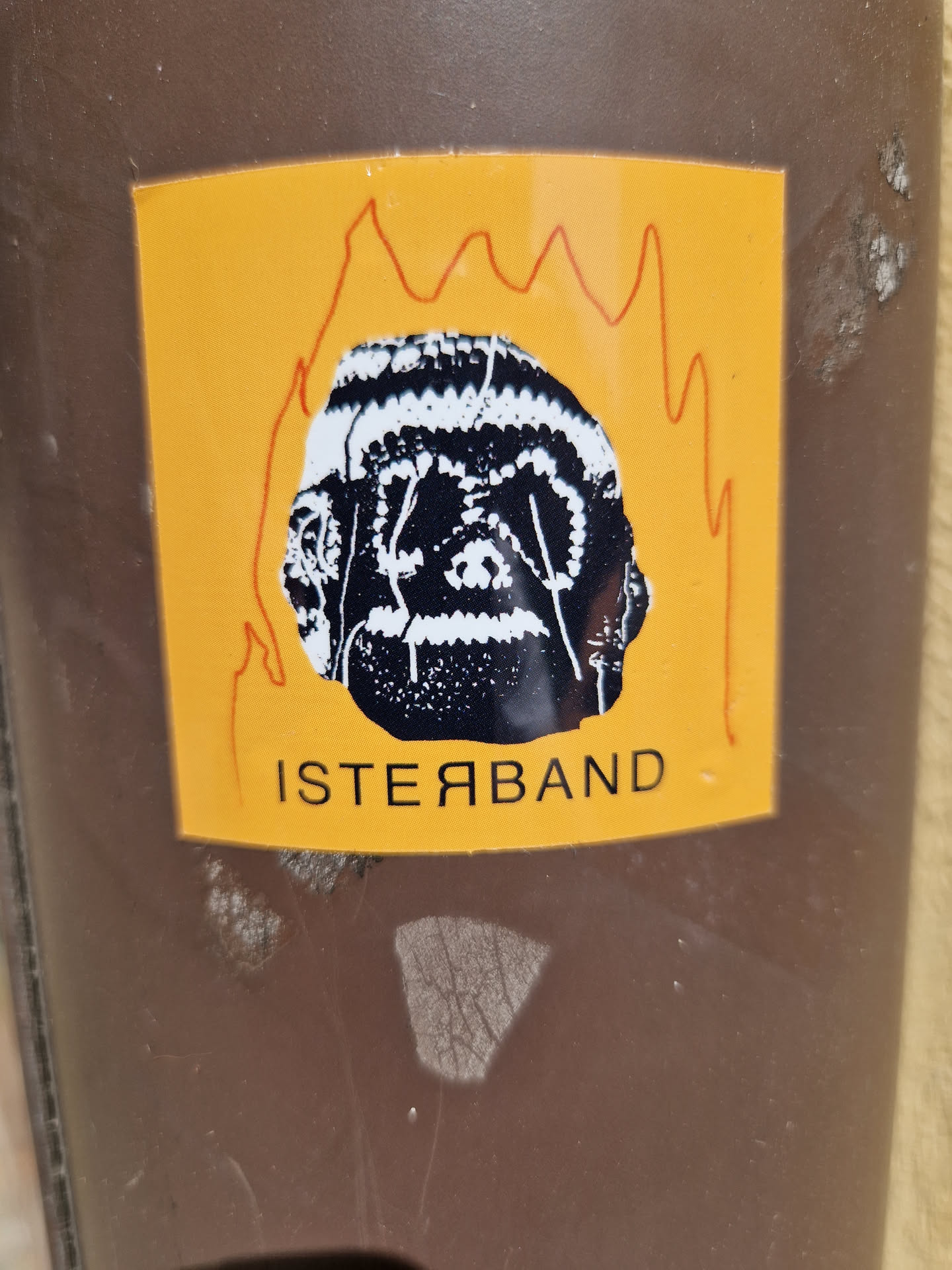 A sticker featuring a black and white illustration of a head engulfed in flames. The head has a textured pattern and the word \"ISTERYBAND\" is written below it in a stylized font. The background of the sticker is yellow.