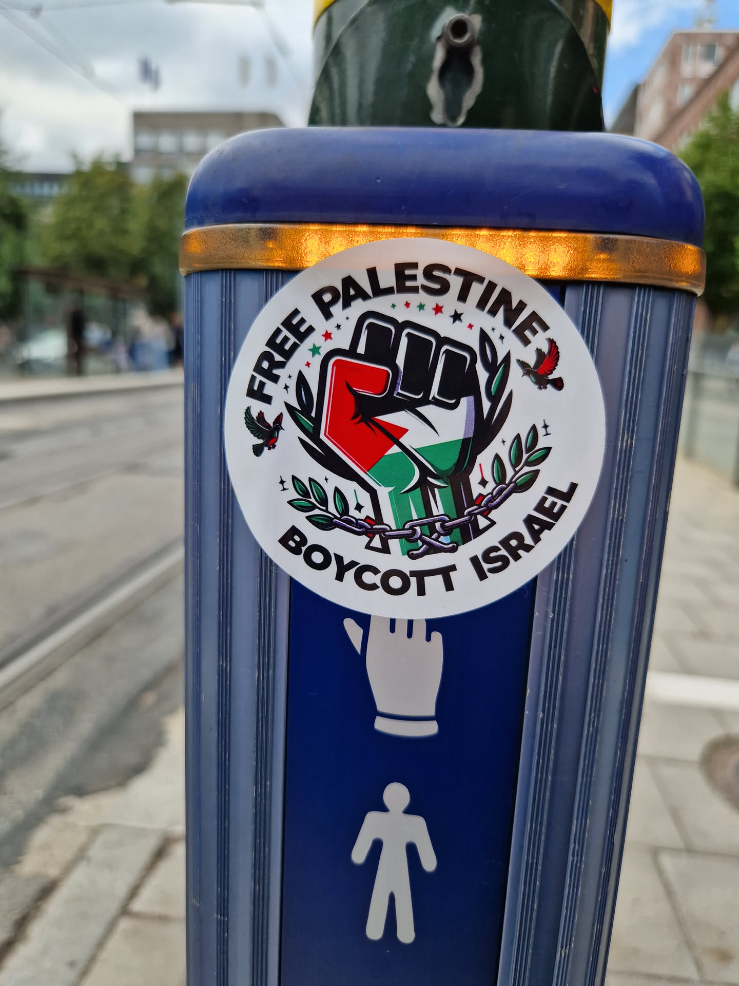 A sticker expressing support for Palestine and calling for a boycott of Israel. It features a fist with the Palestinian flag colors, olive branches, and the words "Free Palestine" and "Boycott Israel".