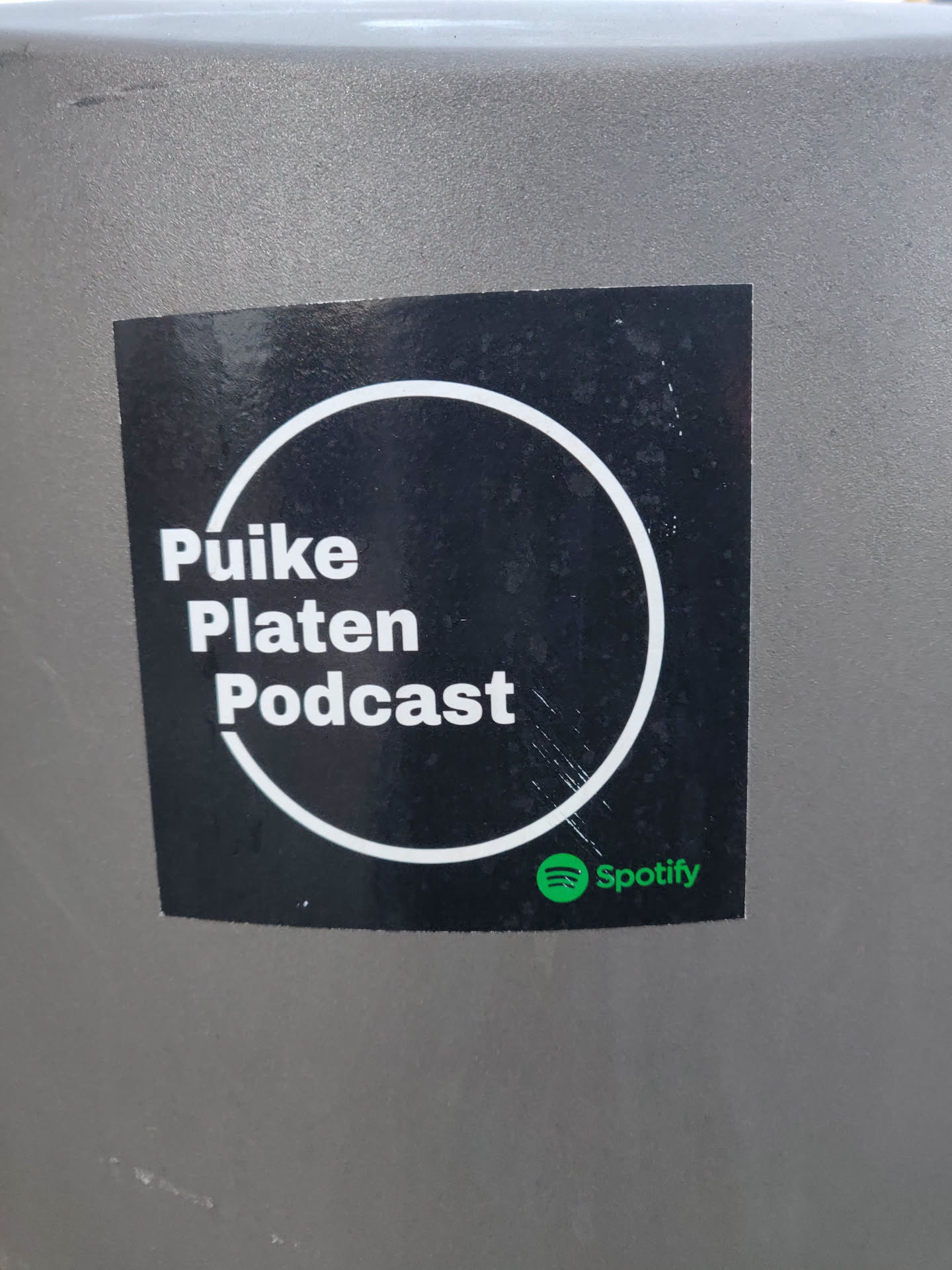 Black and white sticker with the text "Puikie Platen Podcast" in a circle.  Spotify logo is present at the bottom.