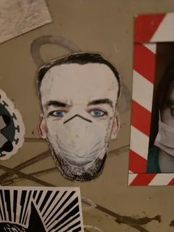 A sticker depicting a man with blue eyes wearing a white N95 facemask. The style is reminiscent of a caricature or a stylized portrait.
