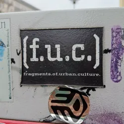 Black and white sticker with the text [f.u.c.] fragments.of.urban.culture. The text is stylized and has a grunge effect.