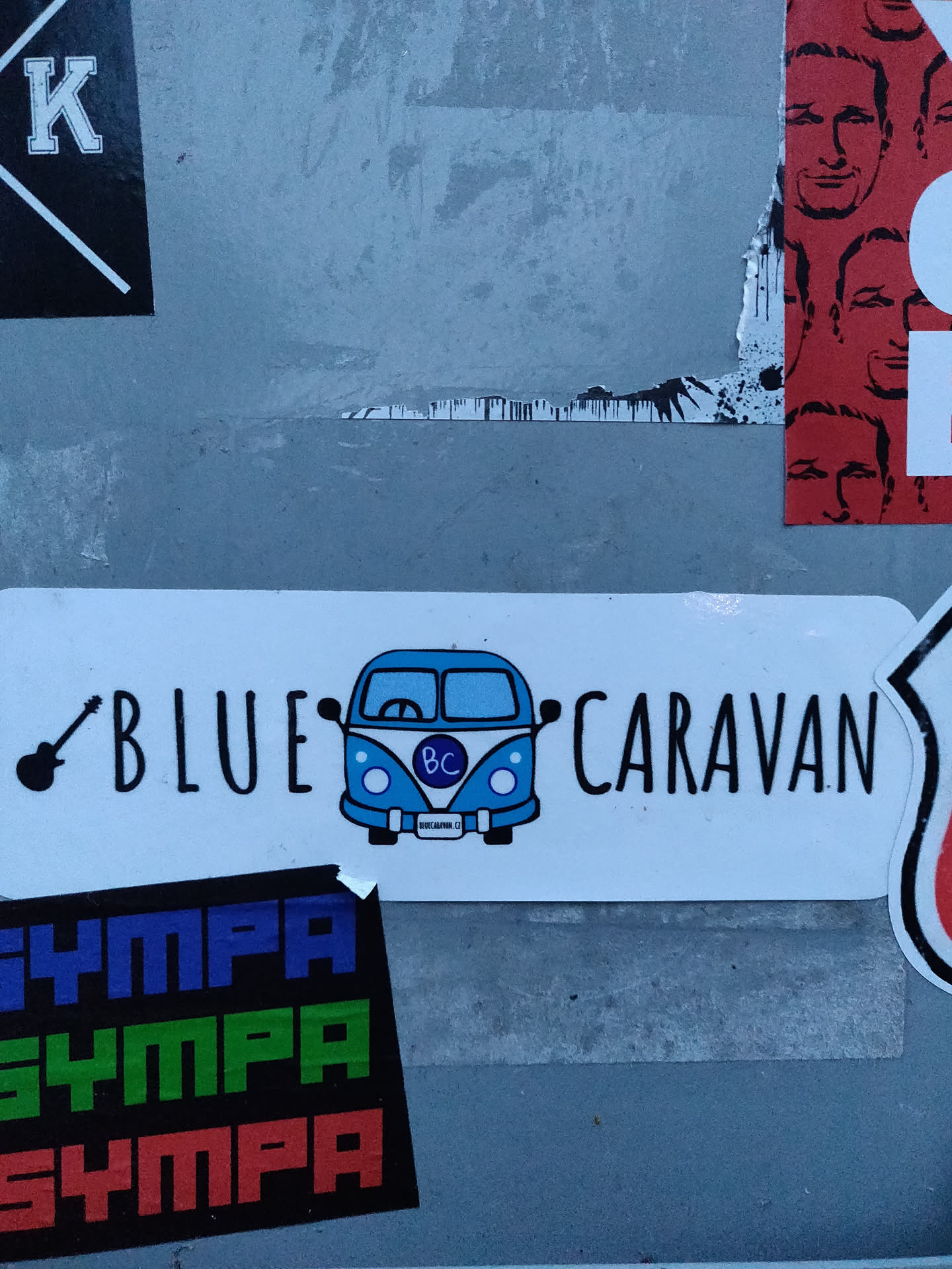 A sticker featuring a blue Volkswagen van with the text "BLUE CARAVAN" and a guitar icon. The van has the letters "BC" on its license plate.