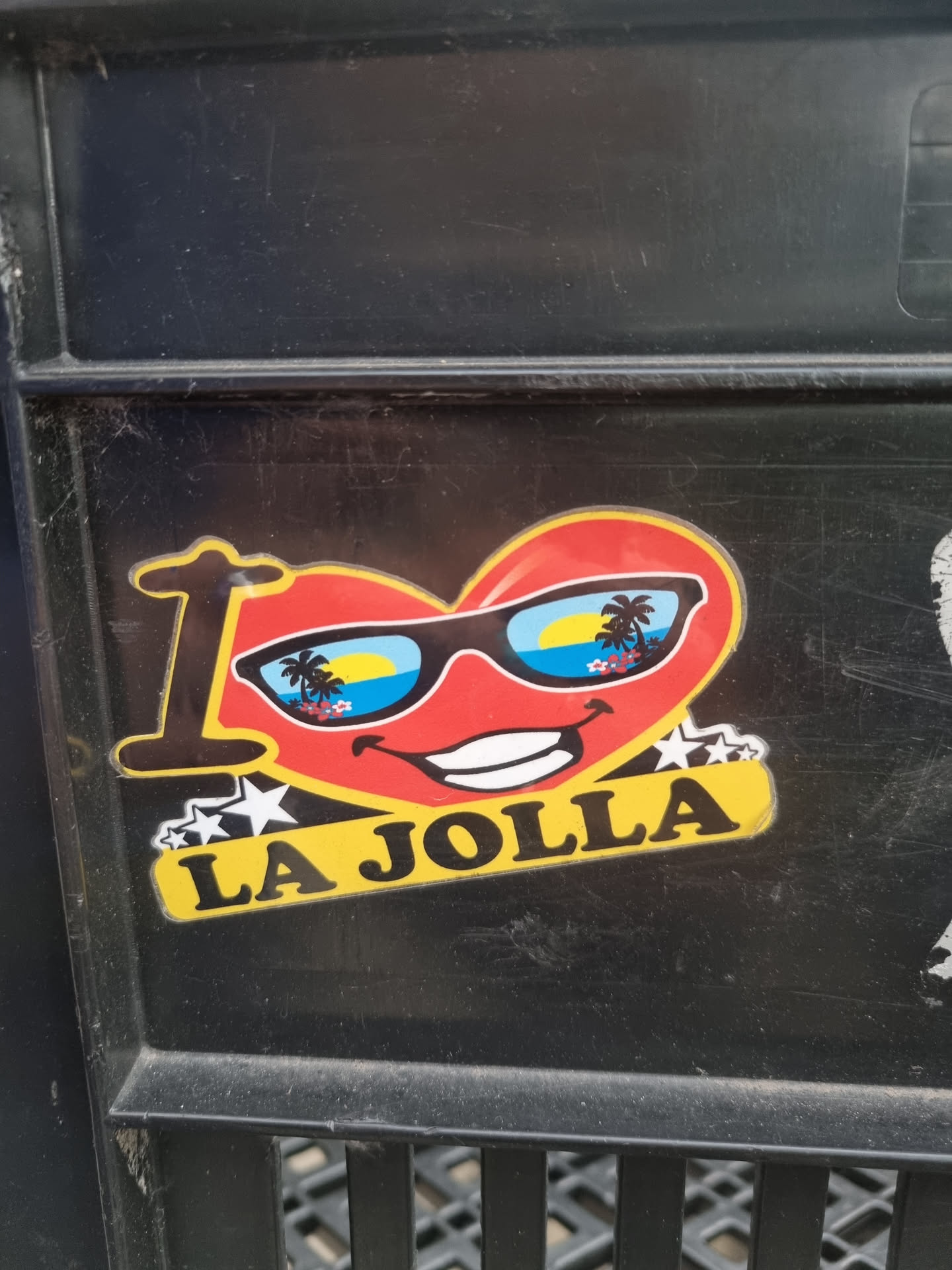 A sticker with a heart-shaped face wearing sunglasses with a beach scene reflected in the lenses. It says "I \u2764 LA JOLLA" with stars on each side of the text.