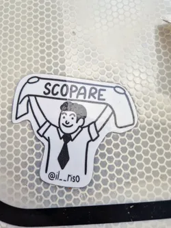 A black and white illustration style sticker features a man holding a banner that says "SCOPARE" in all caps. Below the figure, it reads "@il__riso".