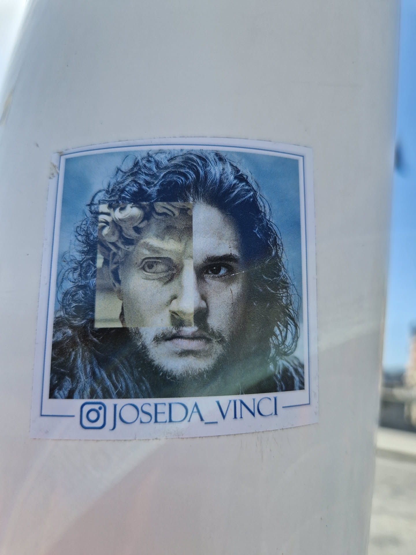 This sticker features a striking image that blends Kit Harington's portrayal of Jon Snow from Game of Thrones with a classical Renaissance statue. The image is expertly collaged to create a seamless visual juxtaposition, playing with ideas of time and artistic influence.  The artist's Instagram handle is visible at the bottom.
