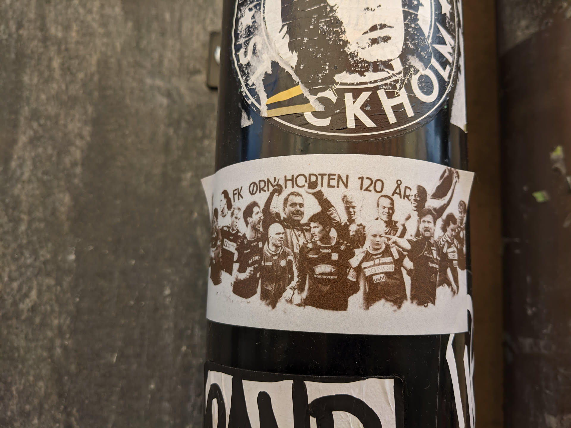 Sepia-toned sticker commemorating the 120th anniversary of FK Örn Horten. It features a group photograph of football players, likely from the team, in a celebratory pose.
