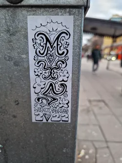 This sticker is a black and white drawing, seemingly hand-drawn, with a central focus on a stylized letter 'M'.  It features a whimsical design with flowers, stars, and abstract shapes surrounding the letter. The artist's name and year are included at the base.