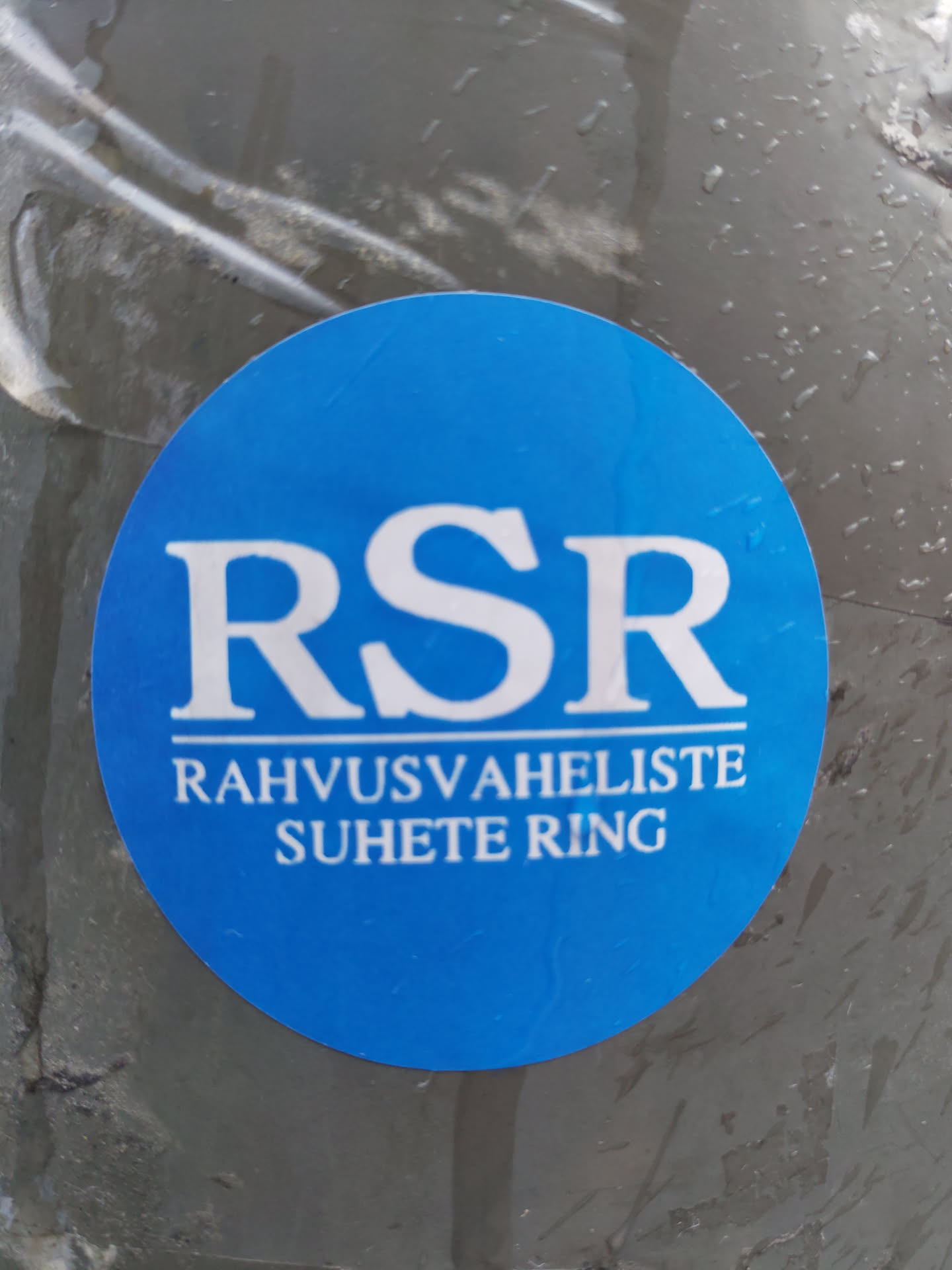 A blue circular sticker with the acronym RSR and the text "Rahvusvaheliste Suhete Ring" (International Relations Ring) in white.