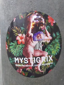 Round sticker with a collage design.  It depicts Atlas, a mythological figure, carrying a large disco ball. The background is a vibrant mix of tropical leaves and flowers. The artist's name, Mystigrix, is prominently displayed at the bottom, along with a Facebook link. 