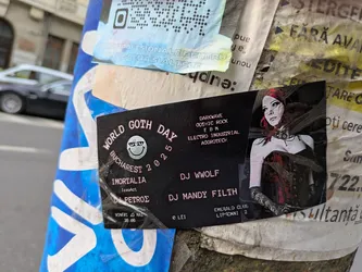 A promotional sticker for the World Goth Day event in Bucharest 2025. The sticker features the date, venue (Emerald Club), and performers (DJ Wwolf, DJ Mandy Filth, and others). The image also contains a stylized illustration of a woman in gothic attire, and promotes music styles like darkwave, gothic rock, EBM, electro-industrial, and agrotech.
