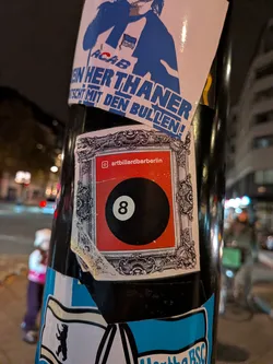 Street sticker A rectangular sticker depicting an elaborate silver-toned antique baroque-style picture frame. Inside the frame, set against a red rectangular background, is a classic black 8-ball. Directly above the billiard ball is the Instagram camera icon alongside the username 'artbillardbarberlin'. The sticker shows slight peeling on the lower left corner.