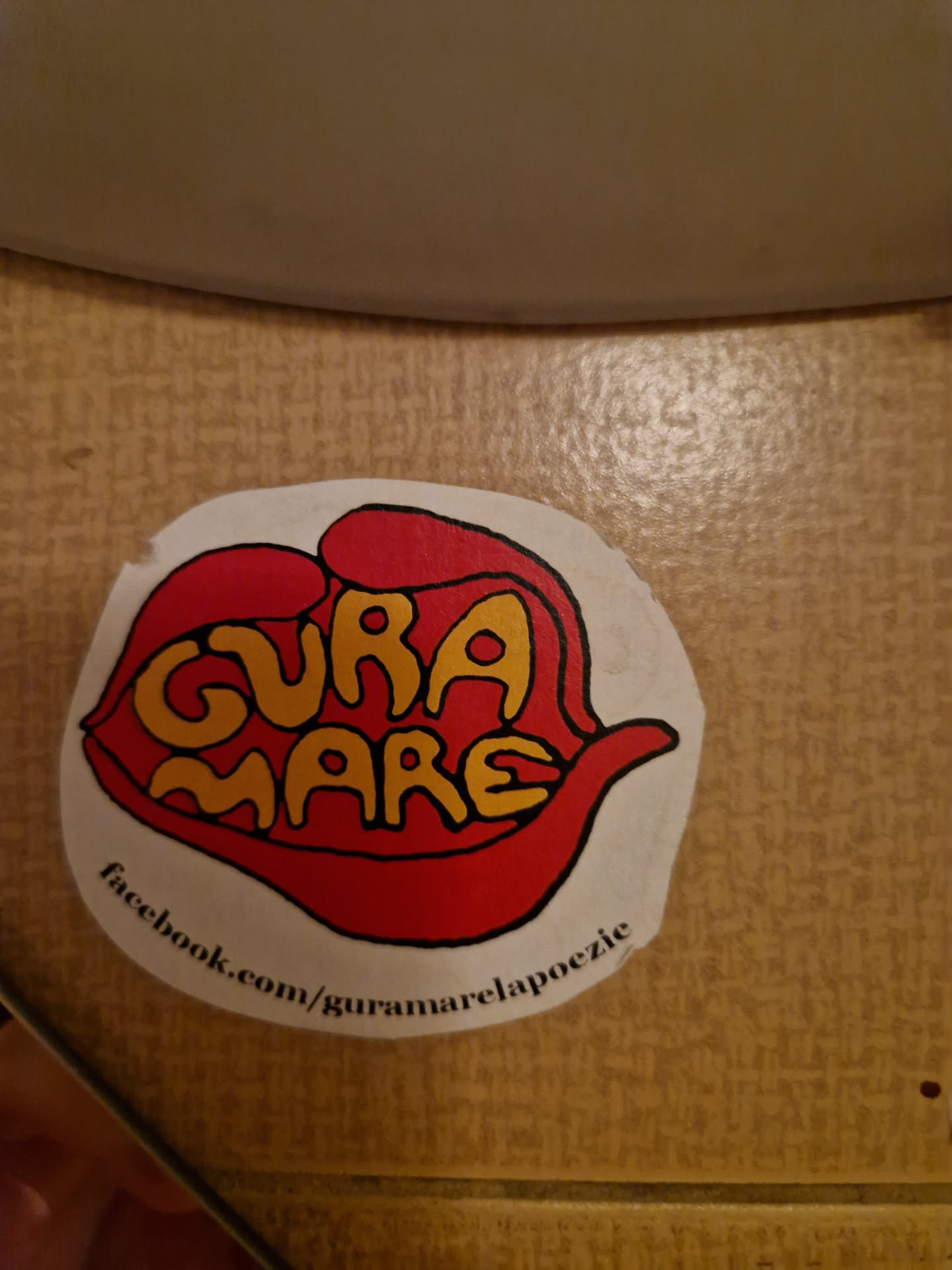 Round sticker with an illustration of a mouth saying Gura Mare. The text is in yellow and red, and the mouth is red. There is a Facebook link at the bottom.