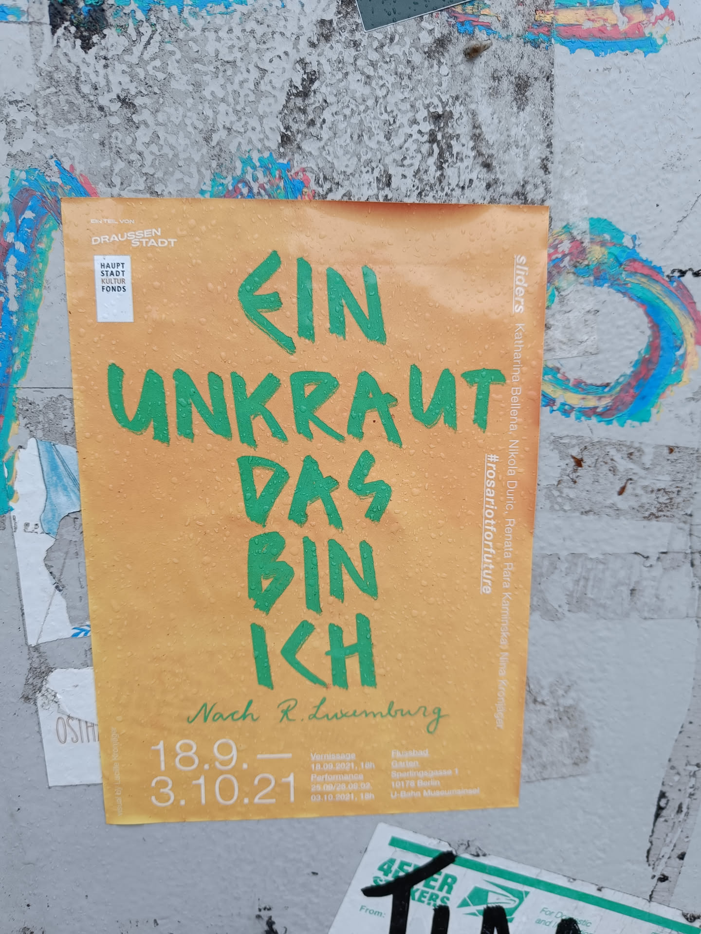 A sticker featuring the text "Ein Unkraut das bin ich" (I am a weed) in green lettering on an orange background. It also includes dates (18.9. - 3.10.21), likely referring to an event or exhibition, and mentions  "Nach R. Luxemburg" (Following R. Luxemburg), suggesting a theme related to Rosa Luxemburg's philosophy.  The hashtag #rosariotforfuture is also visible.