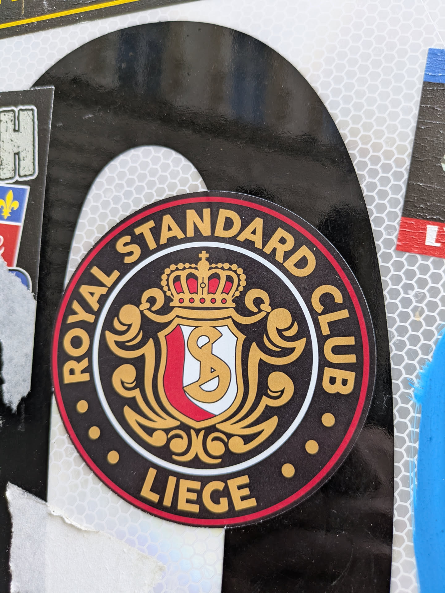 This is a round sticker for the Royal Standard Club Liege, a football club. The sticker features the club's emblem, which includes a crown, a shield with the letters "S" and "C", and decorative flourishes. The text around the emblem reads "ROYAL STANDARD CLUB" at the top and "LIEGE" at the bottom.