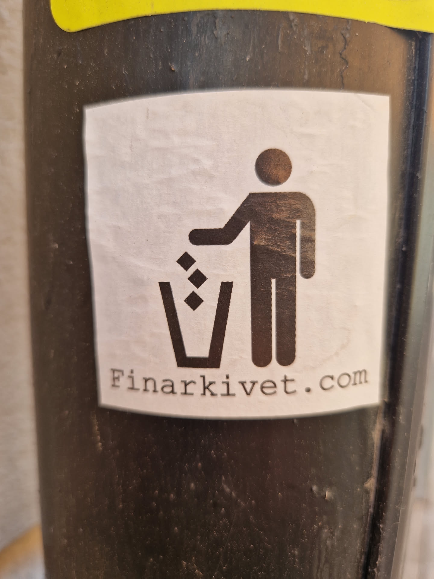 A simple yet effective sticker promoting recycling.  It features a pictogram of a person throwing trash into a bin, along with the website Finarkivet.com.