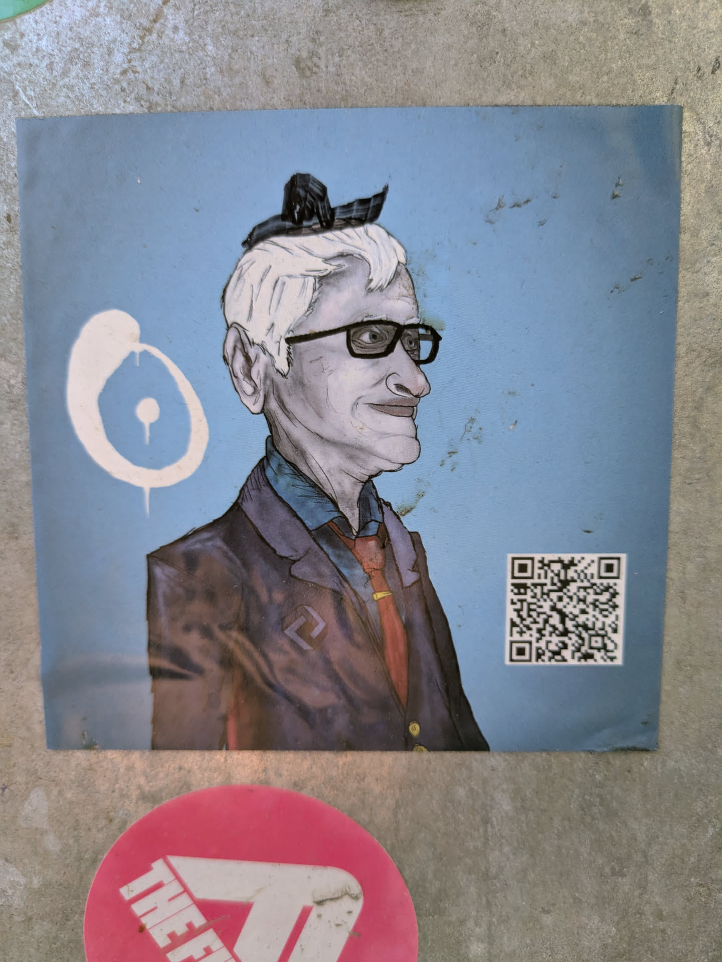 The sticker is a painted portrait of an older man with white hair, glasses, and a suit. There's a QR code on the right side. Next to the portrait is a graphic design of a white circle.