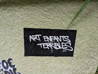 Black sticker with white graffiti-style text. The text says "Art Enfants Terribles".