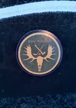 A round sticker with the logo of the Umeå Mooseheads hockey team. The logo features a stylized moose skull with antlers and two crossed hockey sticks. The text "Umeå Mooseheads" is printed around the logo.