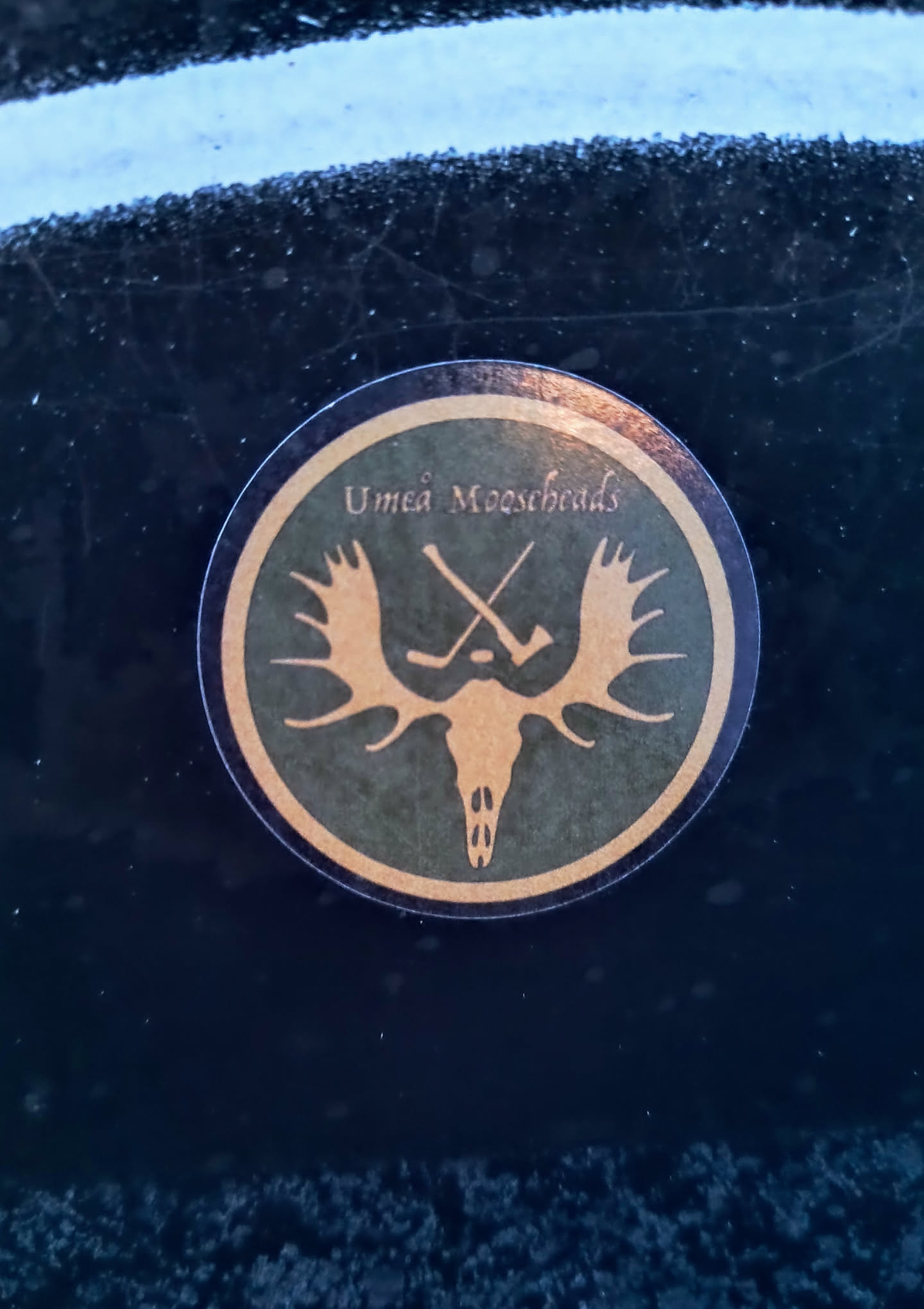 A round sticker with the logo of the Umeå Mooseheads hockey team. The logo features a stylized moose skull with antlers and two crossed hockey sticks. The text "Umeå Mooseheads" is printed around the logo.