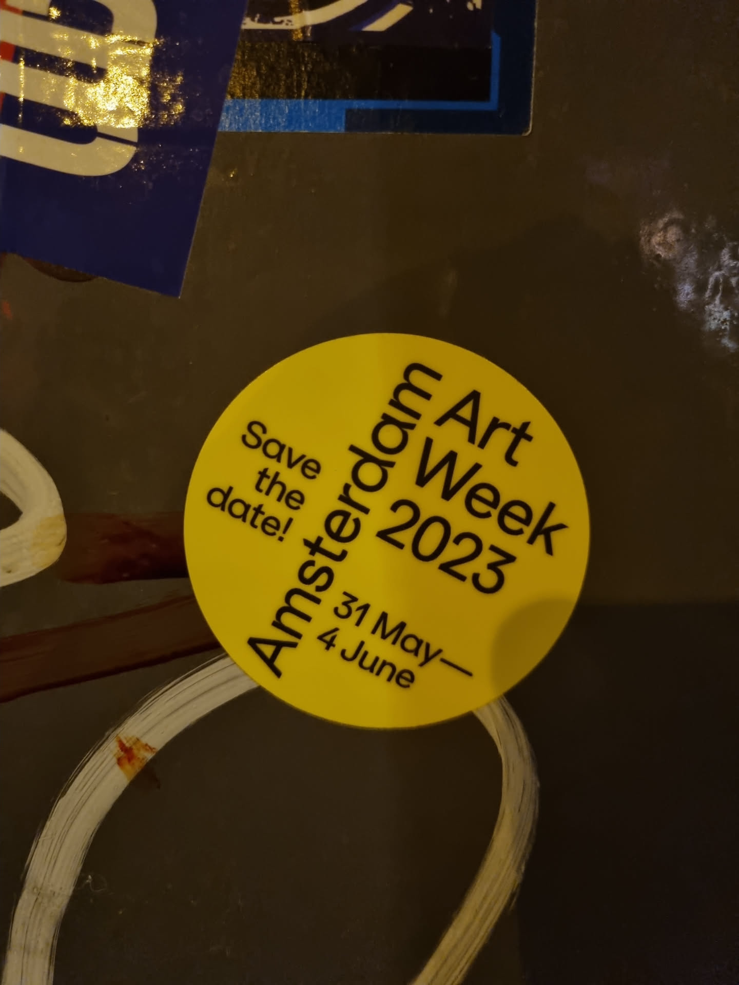 Round yellow sticker announcing the Amsterdam Art Week 2023, taking place from May 31st to June 4th.  The sticker has the text 'Save the date!' above the event details.