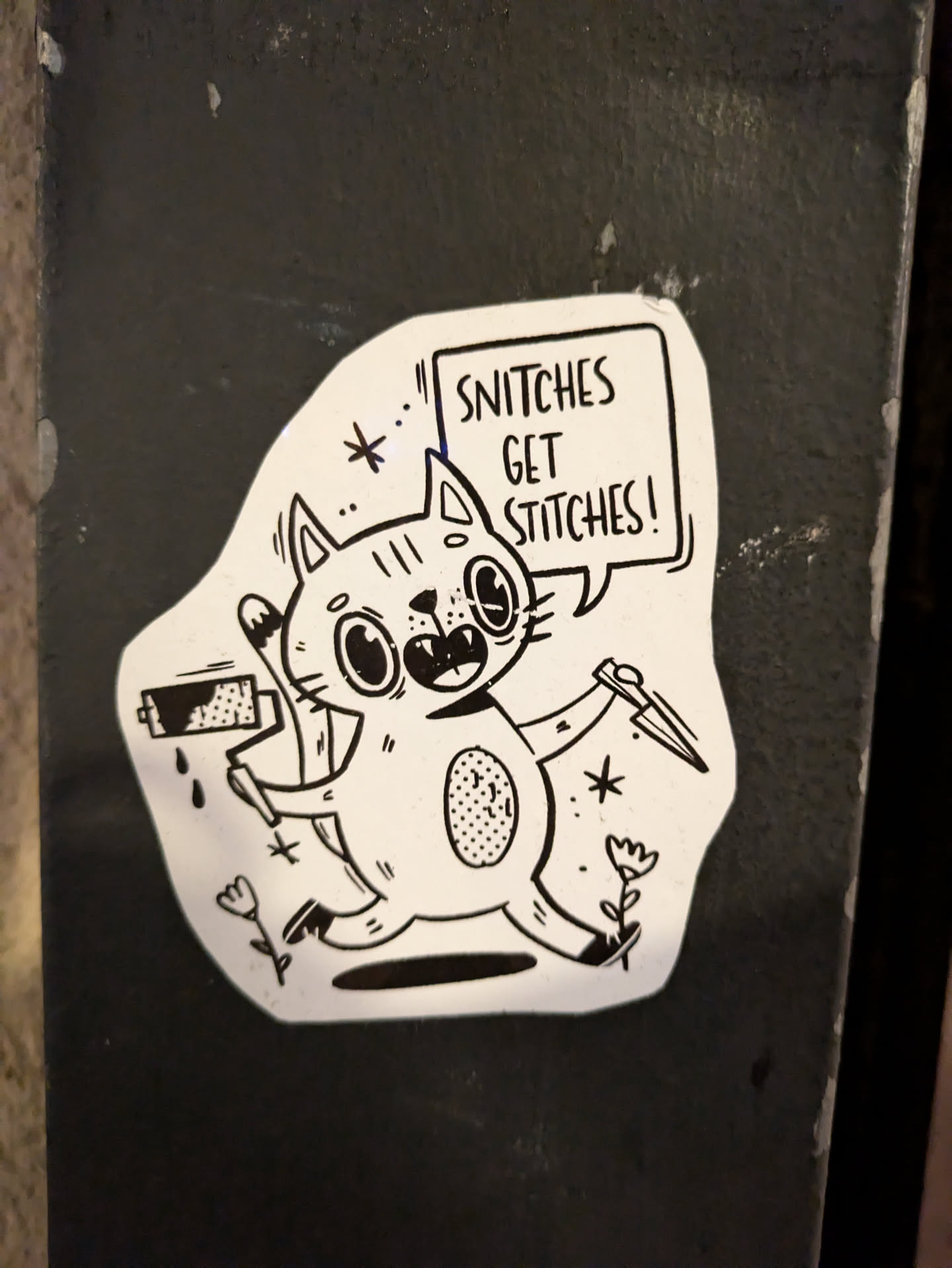 A black and white sticker featuring a cartoon cat holding a paint roller and a knife. The cat has a speech bubble above it that says "Snitch get stitches!"