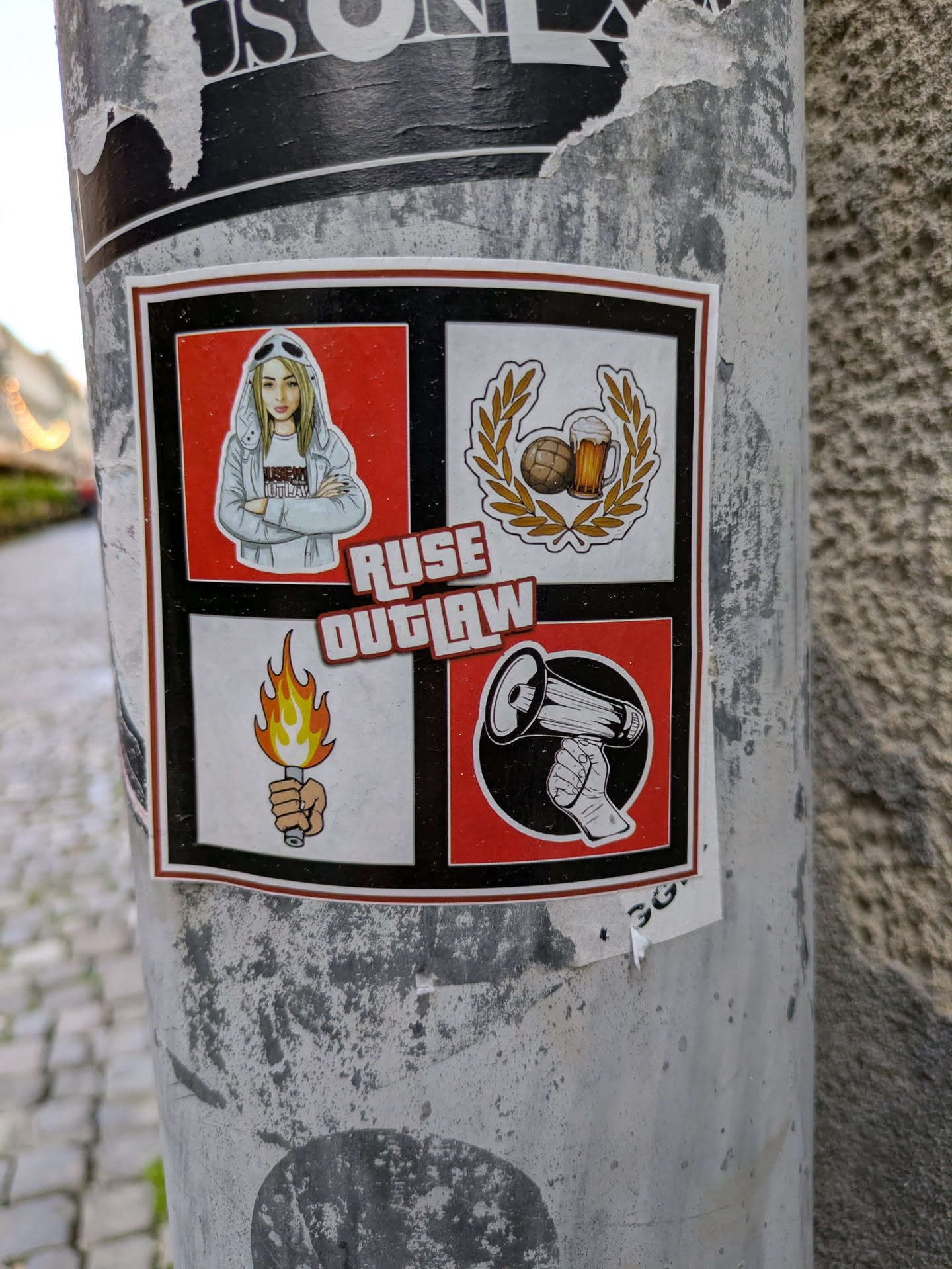This sticker is divided into four quadrants, each containing a distinct image. The first quadrant shows a cartoon-style girl with crossed arms, wearing a hoodie. The second features a soccer ball and a beer mug surrounded by a laurel wreath. The third presents a hand holding a burning torch. The fourth quadrant displays a hand holding a megaphone. The words "RUSE OUTLAW" are printed in stylized red text across the center.