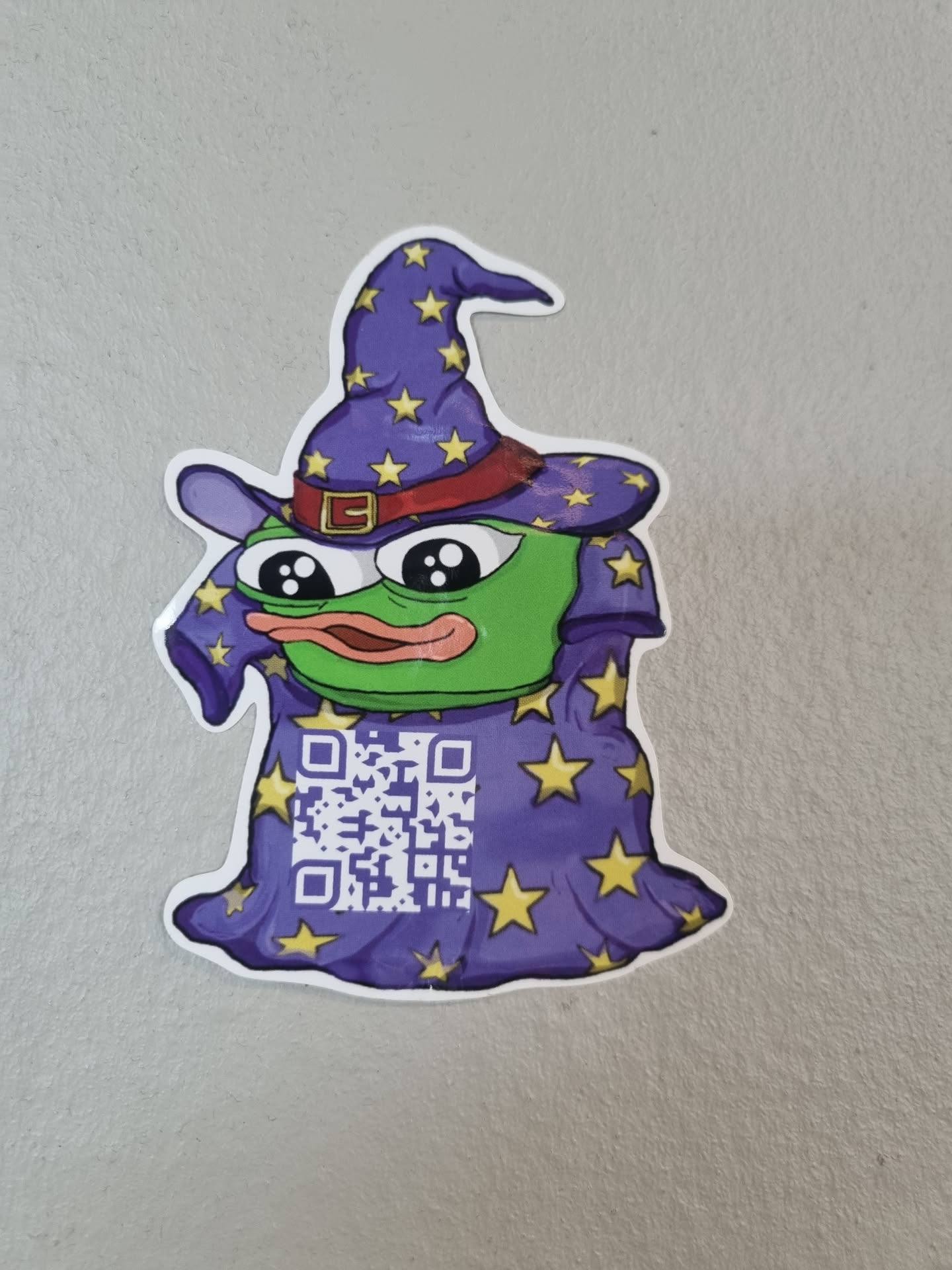 A cute sticker featuring Pepe the Frog dressed as a wizard.  The wizard's robe has a QR code on it.