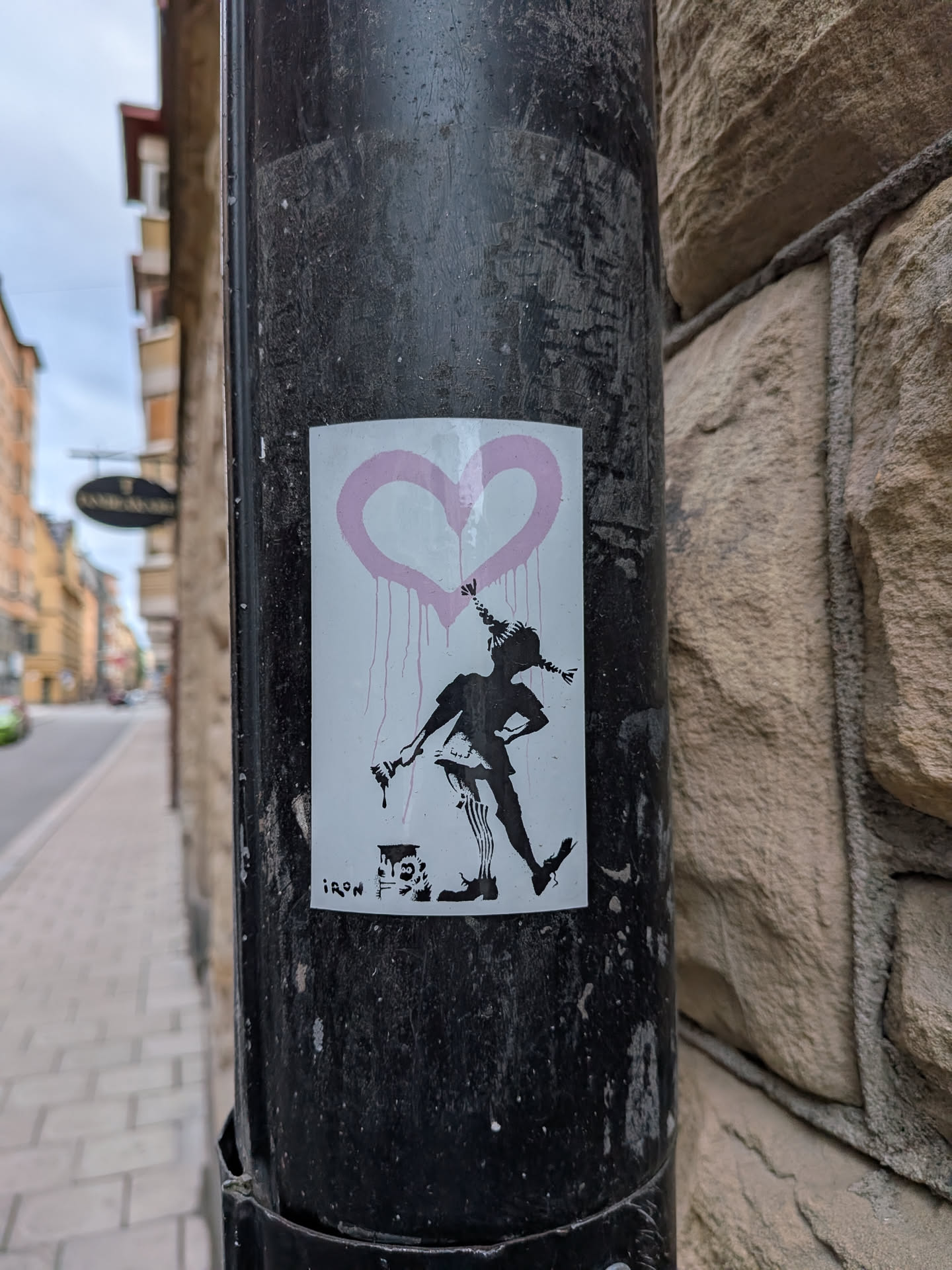 A rectangular white sticker depicting a black silhouette of Pippi Longstocking holding a paintbrush. Above her is a dripping pink heart. A paint can sits at her feet, and the text 'IRON' is printed in the bottom-left corner.