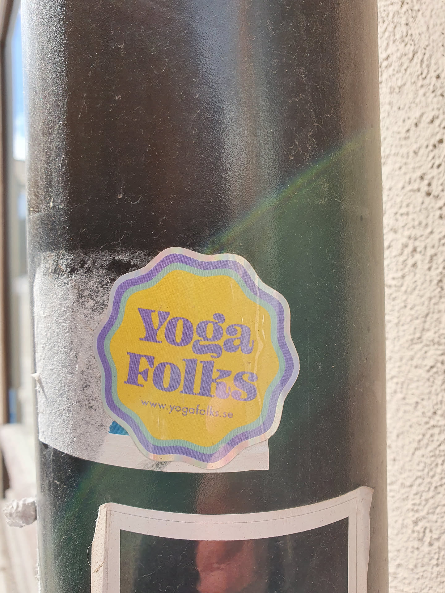 A yellow and purple sticker with the text 'Yoga Folks' and the website address 'www.yogafolks.se'. The sticker has a slightly wavy, flower-like border.
