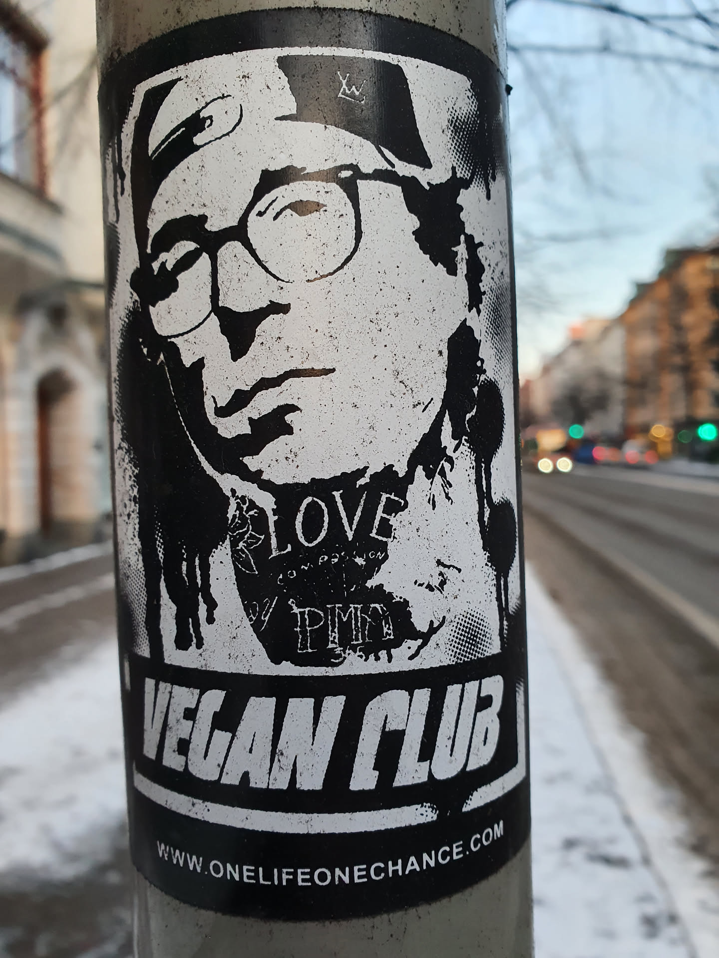Black and white sticker with an illustration of a person wearing glasses and a hat. The text 'Vegan Club' is prominently displayed at the bottom, along with a website address: www.onelifeonechance.com. Smaller text is visible on the illustration, including the word 'LOVE'.