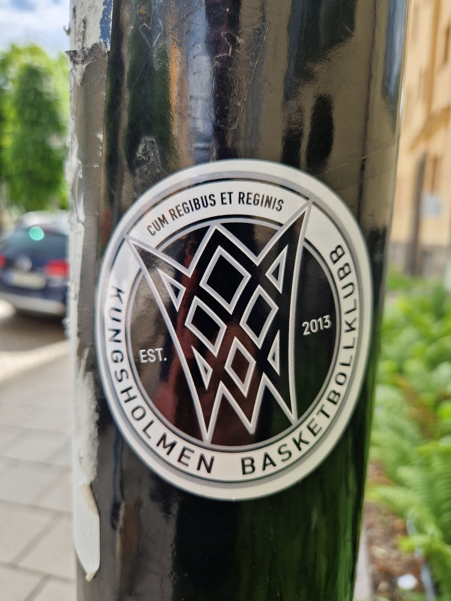 A black and silver sticker featuring the Kingsholmen Basket Klubb logo. The logo includes a stylized geometric design, the club's name, establishment year (2013), and the Latin phrase "Cum Regibus Et Reginis".