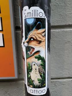 A vertical sticker with the name Emilios Tattoo at the top and bottom. The main illustration shows a snarling fox and a small mouse in a forest setting under a full moon. The art style is reminiscent of tattoo designs.
