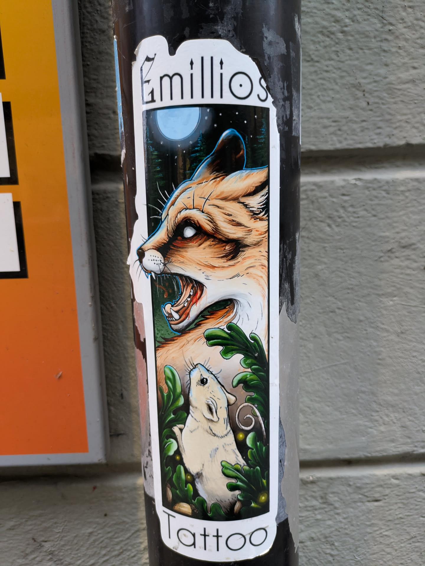 A vertical sticker with the name Emilios Tattoo at the top and bottom. The main illustration shows a snarling fox and a small mouse in a forest setting under a full moon. The art style is reminiscent of tattoo designs.