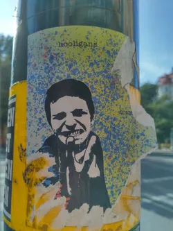 A sticker featuring a stylized black and white illustration of a person, possibly singing or shouting into a microphone. The background is a mottled yellow and blue with a splattered effect. The word "hooligans" is printed at the top.