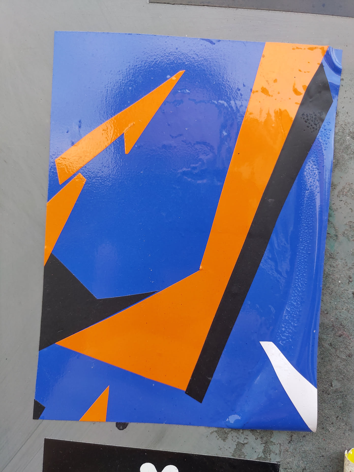 A sticker with an abstract design featuring bold shapes in blue, orange, and black. The design is modern and geometric, creating a visually striking effect. 