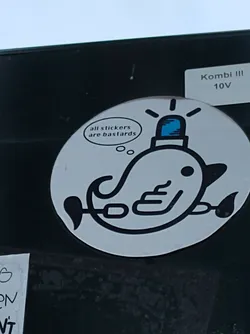Round sticker depicting a stylized whale with a police light on its head. The whale is drawn in black and white, with a speech bubble above it that reads: "all stickers are bastards".