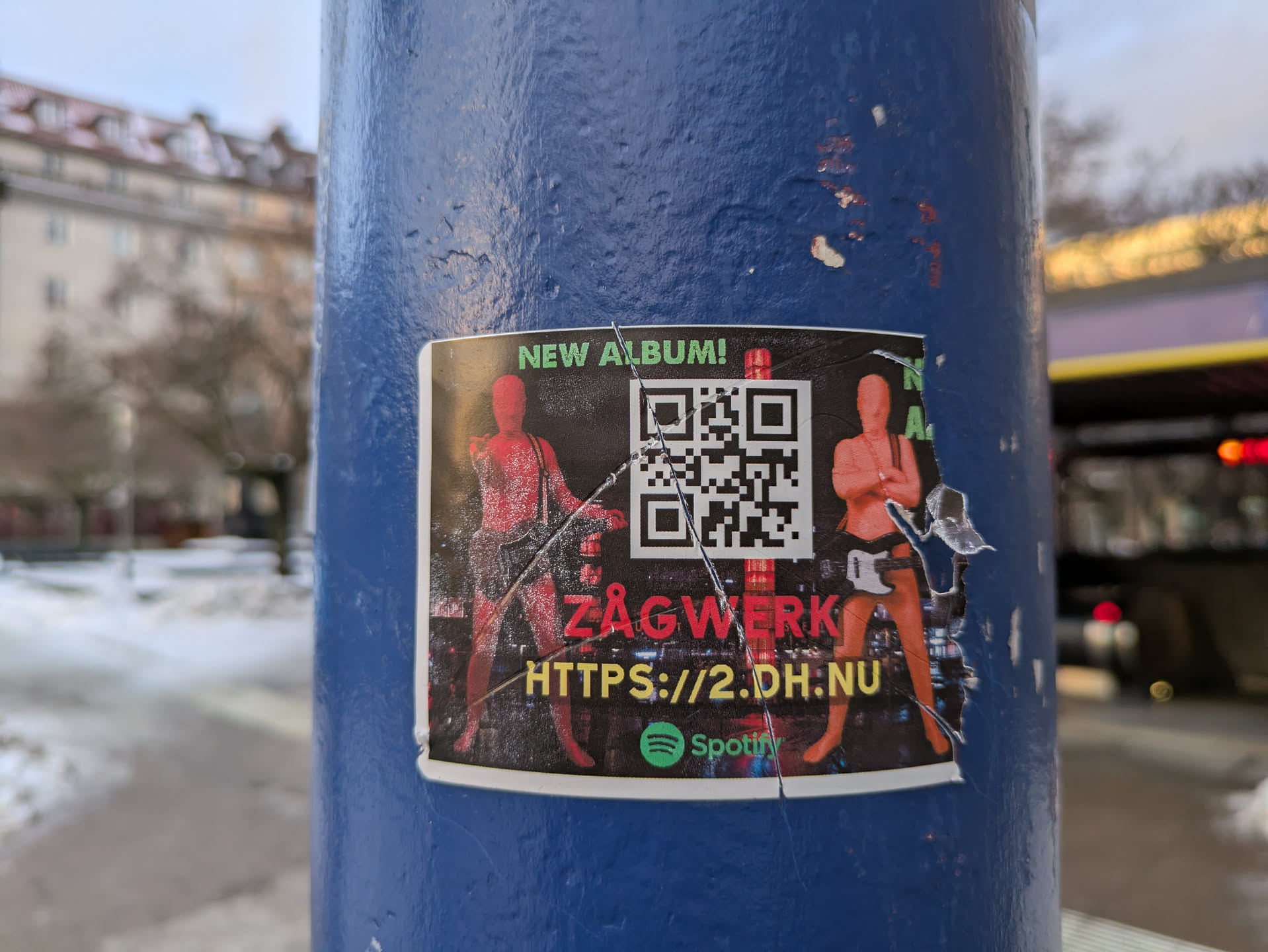 A sticker advertising a new album by the band ZAGWERK.  The sticker features a QR code, a website address, and the Spotify logo.  The design is dark with two figures in red/orange.