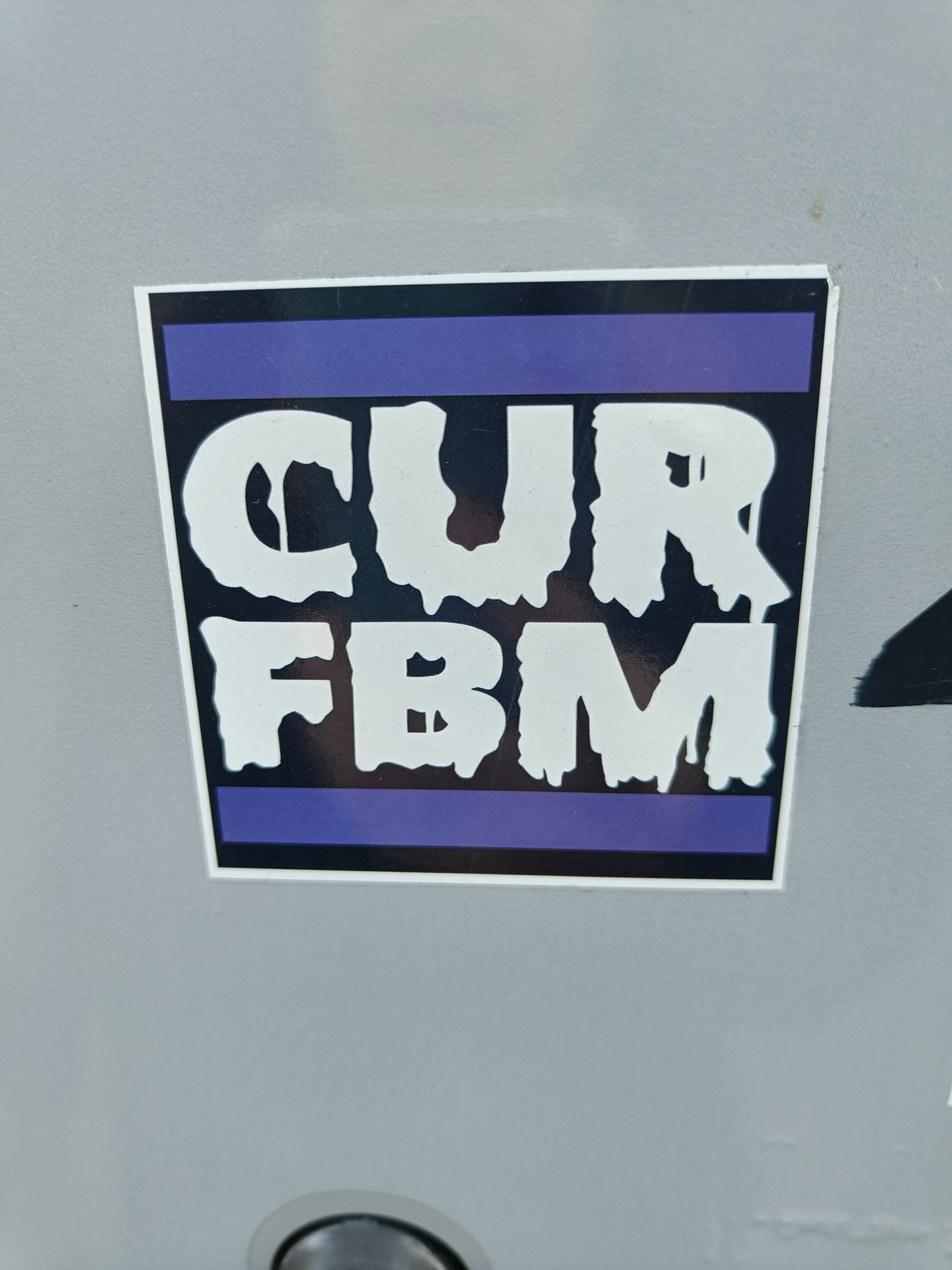 A sticker with the text "CUR FBM" in a dripping style font. The text is white on a black background, with a purple stripe at the top and bottom. 