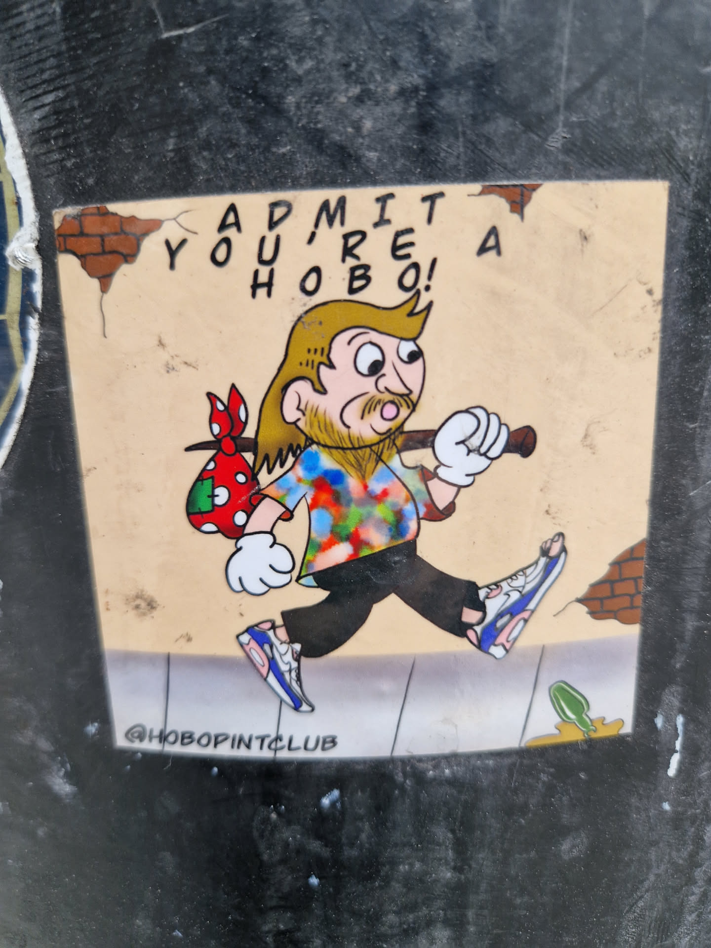 A sticker featuring a cartoon hobo walking, with text that says "ADMIT YOU'RE A HOBO!" and the Instagram handle @HOBOpINTCLUB. The hobo is wearing a tie-dye shirt and sneakers, carrying a bag with polka dots.