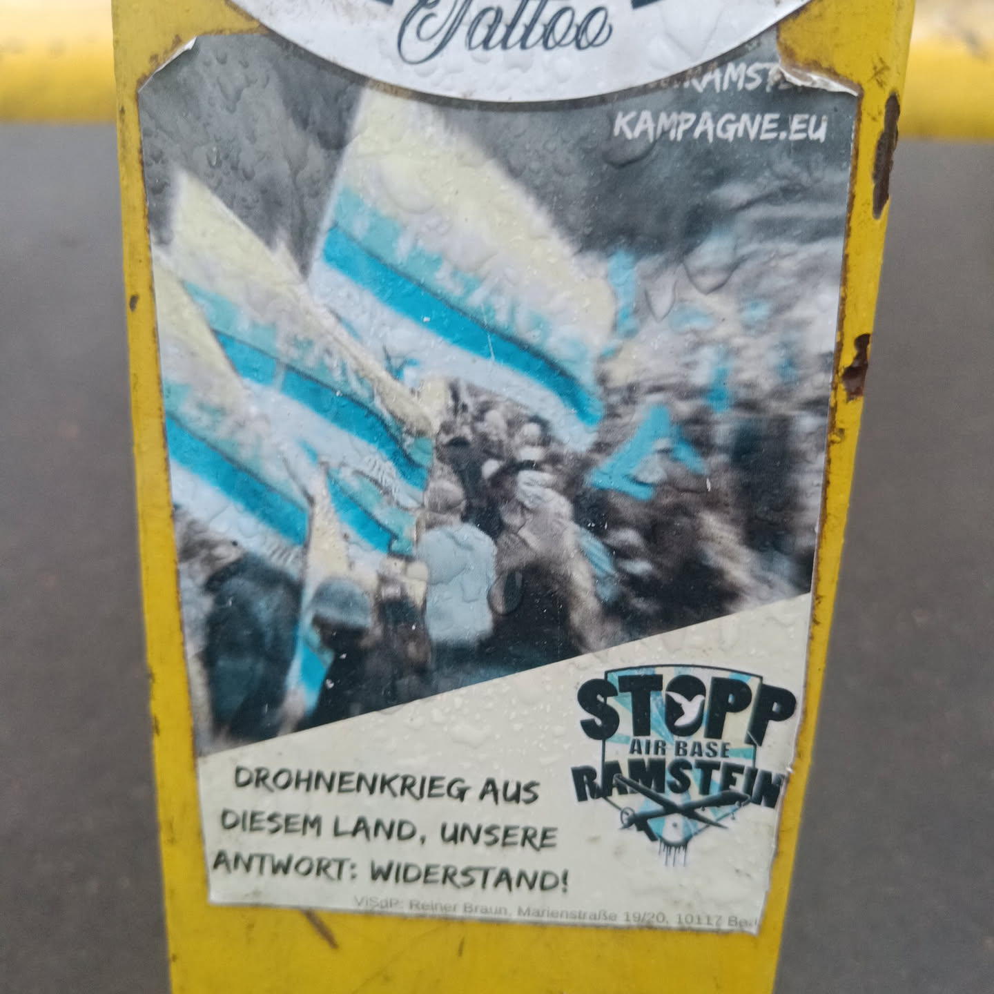 A sticker protesting against the Ramstein Air Base's role in the drone war. The sticker features an image of a protest and the text "STOPP AIR BASE RAMSTEIN" in bold letters.  German text translates to "Drone war from this country, our answer: resistance!"