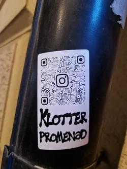 A white sticker with a QR code linking to Instagram and the text 'Klotter Promenad' written in black marker.