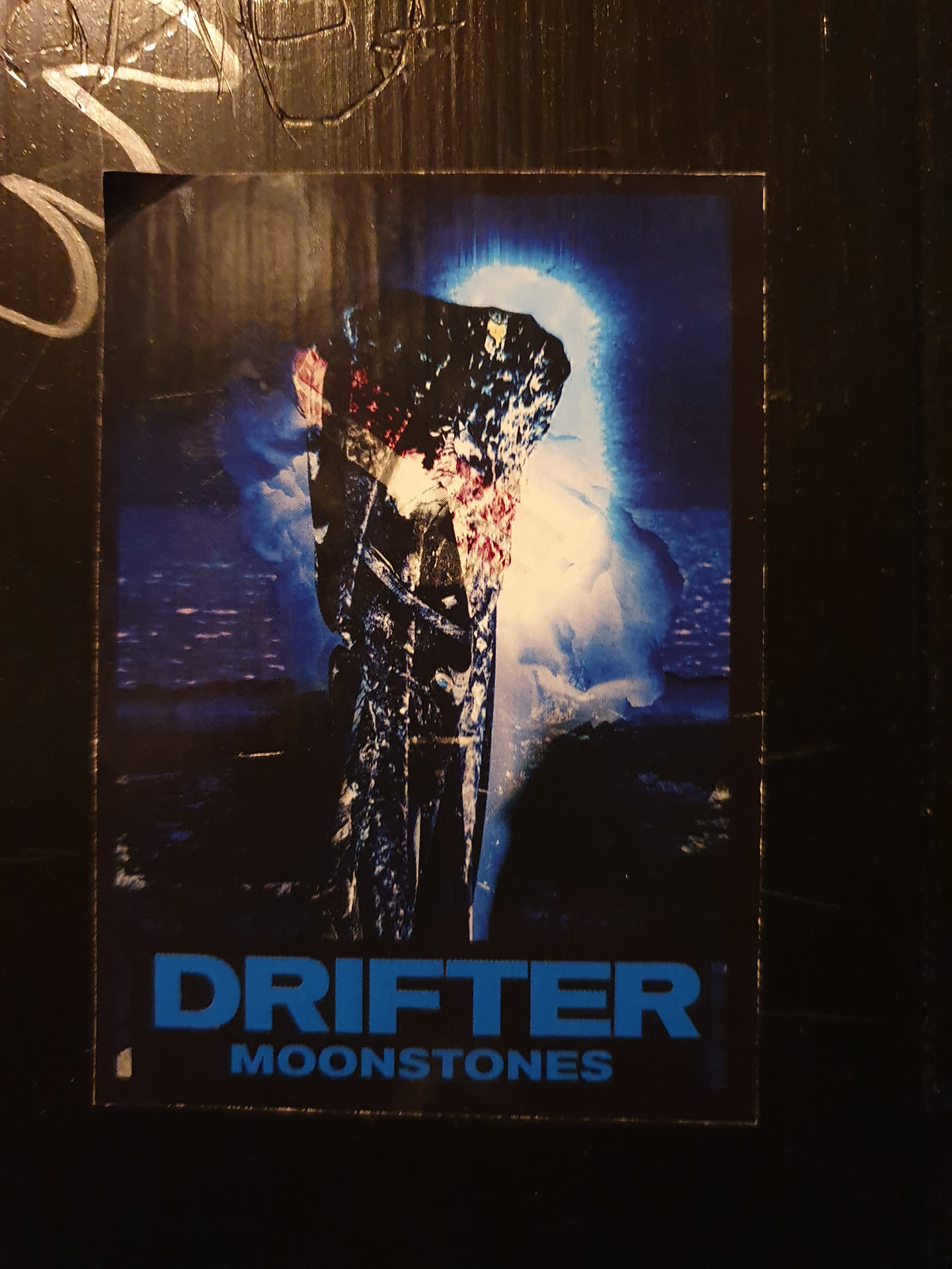 A sticker featuring artwork for Moonstones' song Drifter. The art depicts a dark, almost gothic figure standing on a beach under a blue glow.